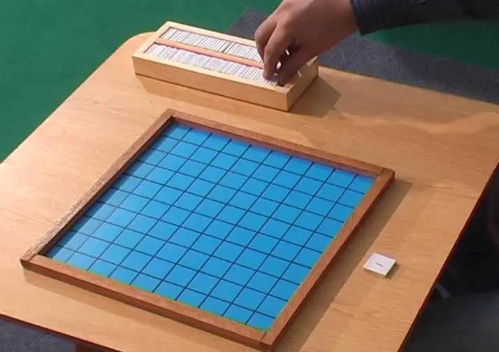 Placing number tiles on the Montessori Hundred Board.