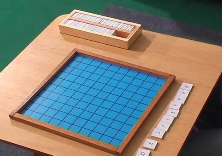 Preparing to place number tiles on Montessori Hundred Board.